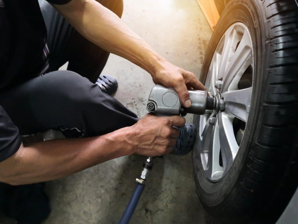 Removing car mechanic to repair the leaky tire car wheels.Mechanic changing a car tire on a vehicle a hoist using an electric drill to loosen the bolts .concept of service or replacement.